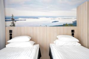 two beds in a room with a view of the ocean at Break Sokos Hotel Koli Kylä in Kolinkylä
