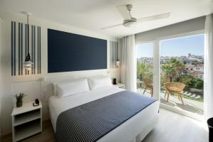 a white bedroom with a bed and a large window at Catalonia Mirador des Port in Mahón