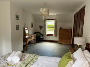 a bedroom with a bed and a desk and a window at The Haven in Saint Fillans