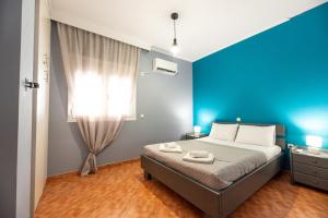 a bedroom with a bed with a blue accent wall at Sea and Airport in Artemida