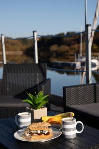 una mesa con un plato de comida y tazas de café en Hausboat Erik, en Hrdoňov