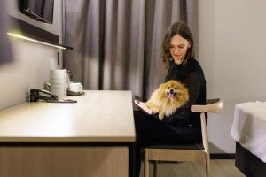 eine Frau, die mit einem Hund im Arm auf einem Stuhl sitzt in der Unterkunft Naalt Hotel Joinville in Joinville + 58 Fotos