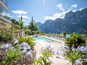 un resort con piscina e montagne sullo sfondo di Hotel Benacus Panoramic a Riva del Garda