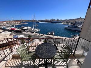 a table and chairs on a balcony with a marina at Igisó in Ermoupoli