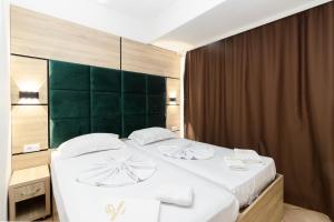 a bedroom with a large white bed with a green headboard at Apartment Hotel Prego in Ulcinj +27 photos