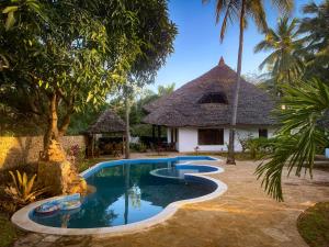 a villa with a swimming pool in front of a house at Kongo Dream in Diani Beach