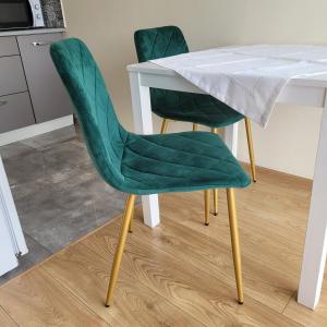 a white table with two green chairs next to it at Oskar Apartament Centrum PKP in Mińsk Mazowiecki