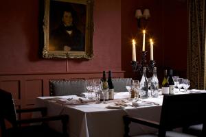 a table with wine glasses and a portrait of a man at The Swan Hotel in Bibury