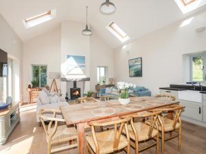 a kitchen and living room with a wooden table and chairs at Traeth Ora in Penrhos-Lligwy