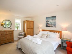 une chambre avec un grand lit blanc et un miroir dans l'établissement Traeth Ora, à Penrhos-Lligwy