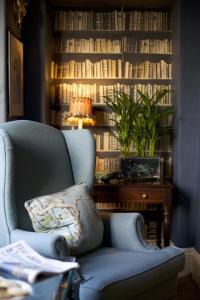 a blue chair and a table with a lamp and books at The Swan Hotel in Bibury