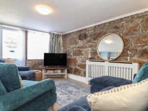 sala de estar con 2 sillas azules y TV en Harbour Studio en Penzance