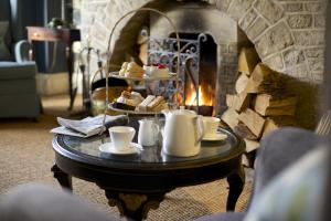 a coffee table with tea cups and pastries in front of a fireplace at The Swan Hotel in Bibury