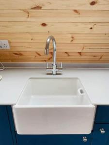 a white sink in a kitchen with a wooden wall at Beach House Pods in Dunoon