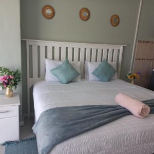 1 dormitorio con 1 cama grande con almohadas azules y blancas en Zufike Self Catering, en Port Elizabeth