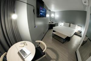 a room with a bed and a table with a laptop at Naalt Hotel Joinville in Joinville