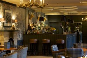 a bar in a restaurant with a fireplace and stools at The Swan Hotel in Bibury