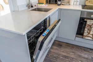 a kitchen with white cabinets and a dishwasher at Gorgeous Hampstead Flat in London