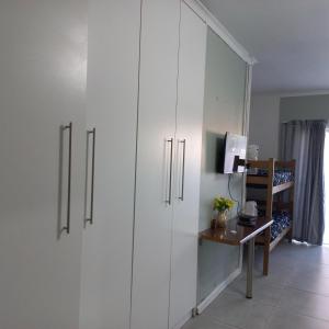 a room with white cabinets and a desk with a television at Zufike Self Catering in Port Elizabeth