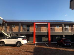 a white car parked in front of a building at Karaboapartlodge in Jane Furse