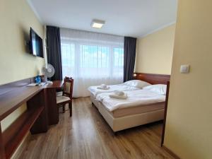 a bedroom with a bed and a desk and a window at Hotel SiLL in Kielce