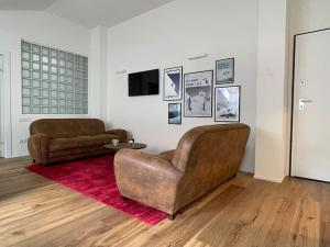 uma sala de estar com uma cadeira de couro e um sofá em Mansarda Malenca em Chiesa in Valmalenco