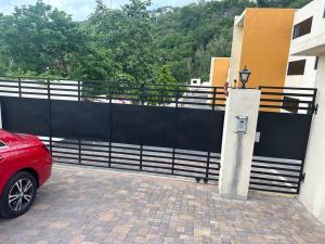 a red car parked next to a black fence at Luxury Comfy Penthouse Red hills in Kingston