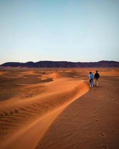 two people walking through the desert at Bivouac ZAGORA in Zagora