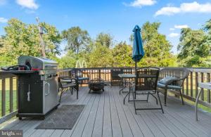 a deck with a grill and chairs and an umbrella at Stafford Virginia Stay in Stafford