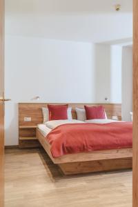 a bedroom with a wooden bed with red pillows at ALPINE Appartement 208 Schladming by globboard in Schladming