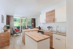 a kitchen with white cabinets and a living room at ALPINE Appartement 208 Schladming by globboard in Schladming