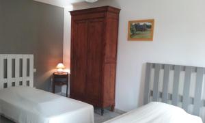 a bedroom with two beds and a wooden cabinet at Maison en Normandie, 130km de Paris in Saint-Germain-des-Essourts