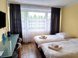 two beds in a room with a glass table and a window at Arkadia in Kielce