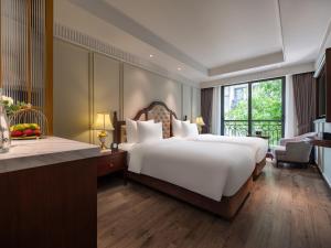 a bedroom with a large bed and a large window at GRAND HOTEL du LAC Hanoi in Hanoi