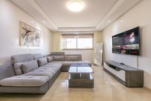 ZARI BOUTIQUE ApartHotel في مراكش: غرفة معيشة مع أريكة وتلفزيون بشاشة مسطحة