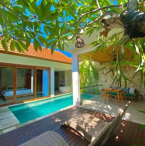 a swimming pool with a table and a house at Danka Villa Sanur in Sanur