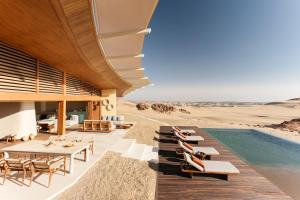 ein Resort in der Wüste mit einem Pool, Tischen und Stühlen in der Unterkunft Six Senses Southern Dunes, The Red Sea 