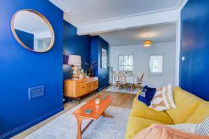 a blue living room with a yellow couch and a mirror at Pass the Keys Cosy house on the seafront in Southend-on-Sea