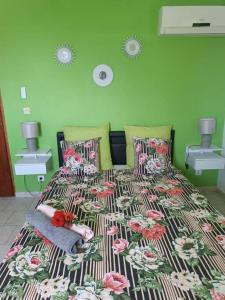 a bedroom with a bed with a floral bedspread at Bas de villa (T4) proche de la plage in Bouillante