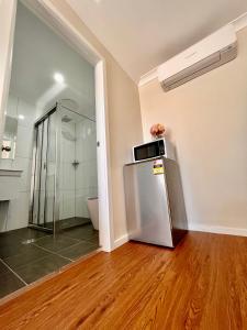 a room with a refrigerator and a glass shower at Seven Inn in Wagga Wagga