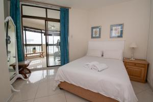 ein Schlafzimmer mit einem weißen Bett und einem Fenster in der Unterkunft 31 Cormoran Umhlanga Rocks in Durban