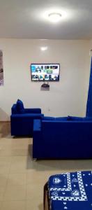 a living room with blue couches and a flat screen tv at RÉSIDENCE NGUARY in Dakar