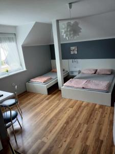 a bedroom with two beds and a table and a desk at Przystań Jagoda - pokoje i domki in Ostrowo