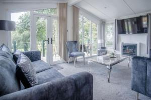 1 Manor Lodge - 3 Bedroom Lodge - Pendine في بينداين: غرفة معيشة مع أريكة زرقاء وطاولة