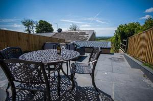 a patio with a table and chairs on a balcony at Anchor Well - 2 Bedroom Cottage - Ludchurch in Ludchurch