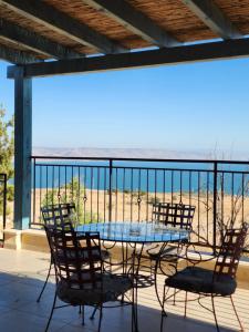 een tafel en stoelen op een balkon met uitzicht op het strand bij מול הכנרת Over looking the Sea of Galilee in Chorazim