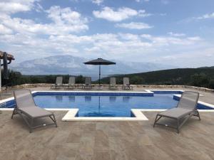 a swimming pool with two chairs and an umbrella at Ferienhaus Luisa Insel Brac - Kamin, Pool, Grill, Olivengrundstück in Pučišća