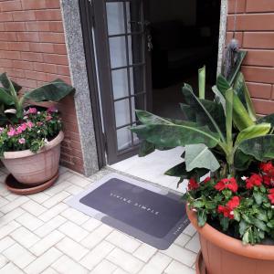 una alfombra de bienvenida frente a una puerta con plantas en Le Case del Cortile, en Catania