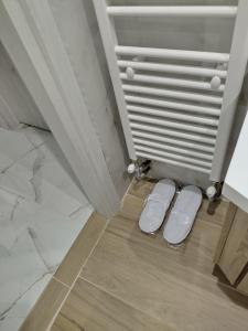 twee witte slippers op de vloer voor een deur bij Εlite Αpartment Trikala in Tríkala