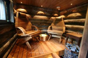 duas cadeiras de madeira e um banco numa cabina em Holiday Home Aurora Cabin em Luosto
